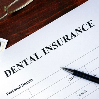 Top of dental insurance form with money, pen, glasses, and X-rays