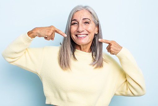 Happy mature woman pointing at her teeth