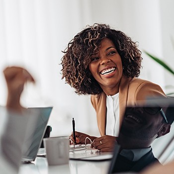 Woman smiling while taking notes during meeting