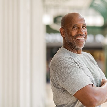 Man in gray shirt smiling outside